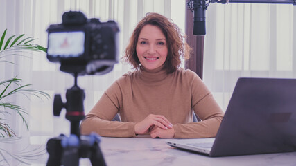 Smiling woman recording her video blog. Woman blogger videotapes her vlog at home.  Adult woman...
