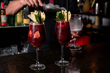 A young professional bartender prepares cocktails for his clients at work. profession concept