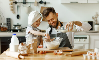 Happy man with kid preparing dough at home.