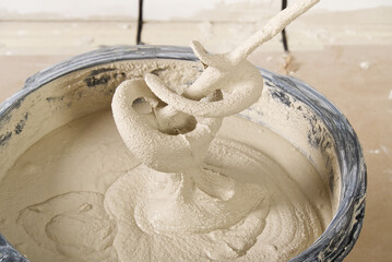 the master mixes the plaster in a bucket. Flat house renovation, master mixed the mortar in a plastic bucket with mixer