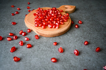 Ripe pomegranate seeds on a cutting board on the table