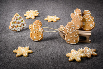 Ginger cookies. Ginger cookies in the form of snowman in a winter sleigh. Grey background.