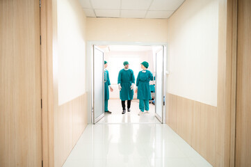 surgical team in masks and uniform keeping arms crossed and looking at camera while standing in operating theatre together.