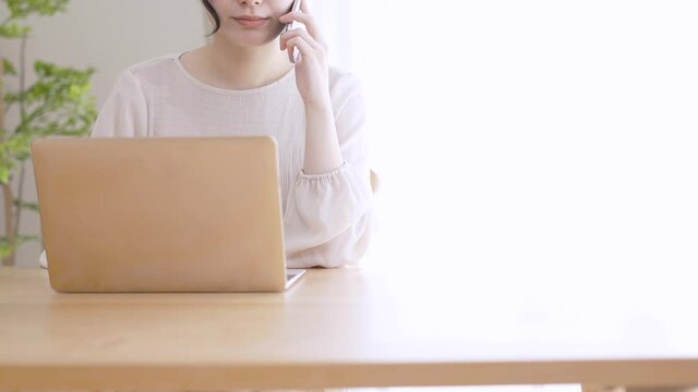 電話をしながらラップトップを使う若い女性