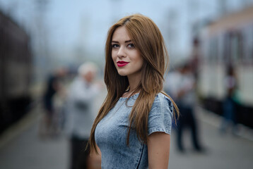 Fototapeta premium Beautiful young brunette woman with blue dress on a street urban background