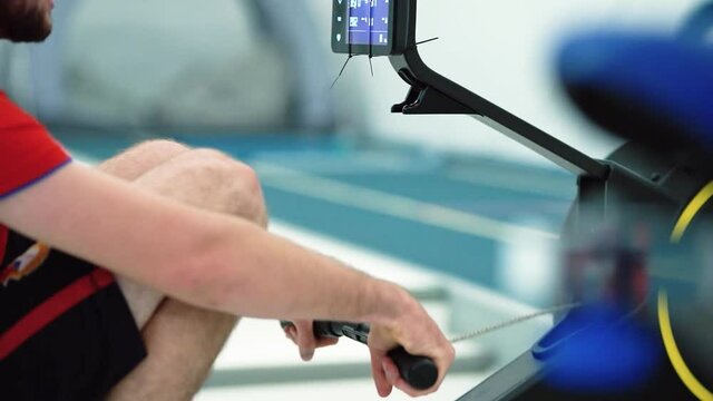  Professional athlete rower training on magnetic rowing machine. Man workout row in gym