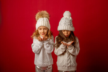 Fototapeta premium 2 little girls on a red background blowing snow