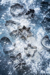 Christmas baking - cookie cutters and flour on dark background
