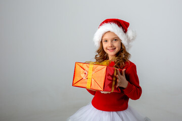 a girl in a Santa hat on a white background holds a gift