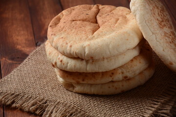 A stack of pita breads. Pita bread on wooden board, Arabic bread, soft baked flatbreads. Popular Israeli food