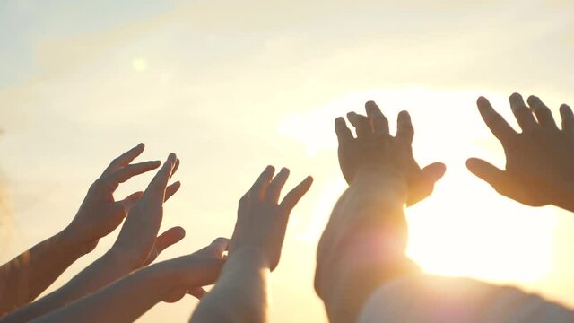 People's hands reach out to the sun and god at sunset. Happy family together hands up religion. Teamwork. Prayer for help. People turn to God together in prayer. People in religion. Helping hand sun