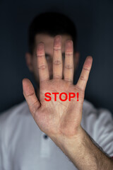 Hand mit roter Stop Schrift vor Gesicht 