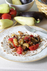Vegetable dish made from fresh peppers, eggplant and tomatoes stewed in pita bread on a plate on the table