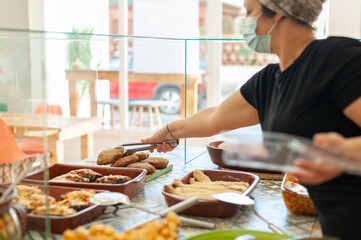 Take away owner serving food wearing a surgical  mask. New normal concept.