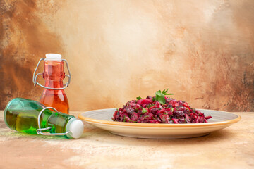 Side view of delicious salad with beetroot and bean and fallen two oil bottles on mixed color background