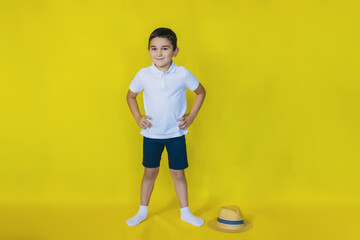 Fototapeta na wymiar A small boy in a white shirt stands on a yellow background.the concept of recreation and tourism.In the school holidays.