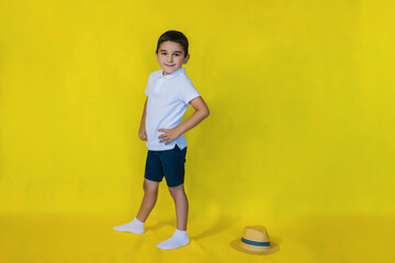 A small boy in a white shirt stands on a yellow background.the concept of recreation and tourism.In the school holidays.