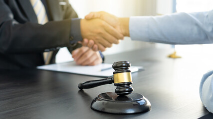 Lawyers hammer on a forward table with a judge and client shaking hands behind the scenes in the legal courtroom.