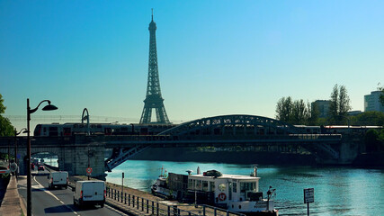 Fototapeta na wymiar Paris traffic with view of Eiffel Tower and metro train on Bir-Hakeim metal bridge in the morning
