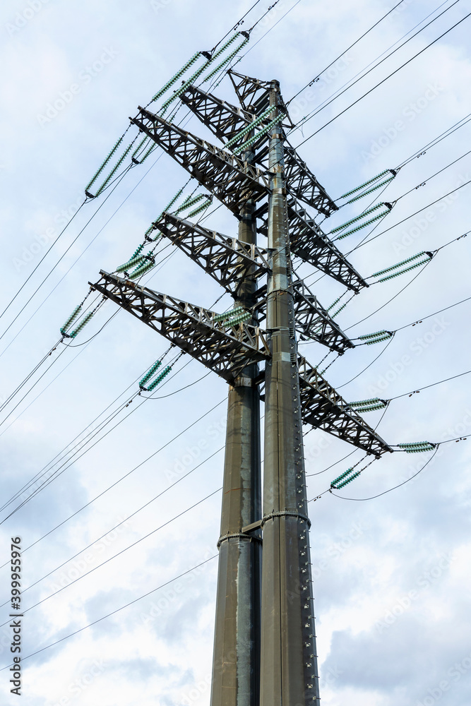 Wall mural high-voltage powerful electricity tower with wires against clouds and blue sky.