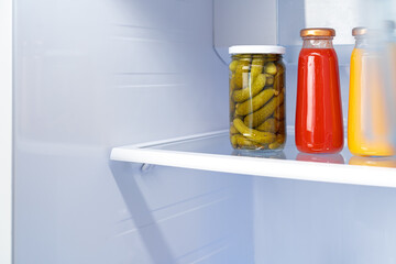 Glass jars of canned products on a fridge shelf