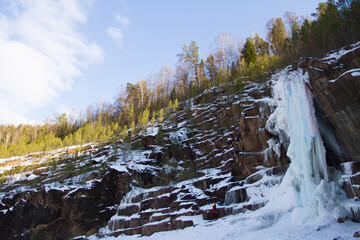 Rock climber climbs the winter frozen waterfall