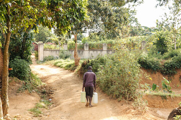 Fototapeta na wymiar Man carrying water cans in Uganda, Africa