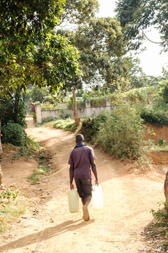 Man carrying water cans in Uganda, Africa