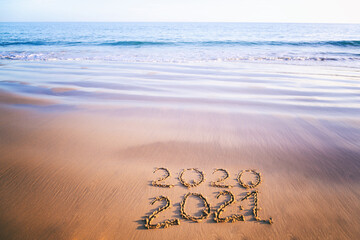 2021 year message handwritten in sand on beautiful beach background. New Years concept.