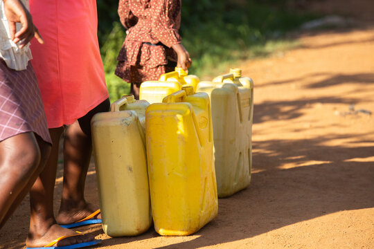 People filling water cans at a well in Uganda, Africa