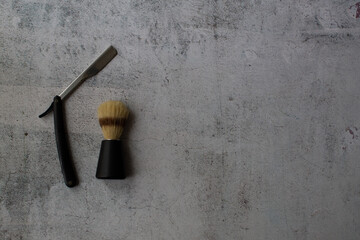 barber's brush and razor on the left side on a grey background