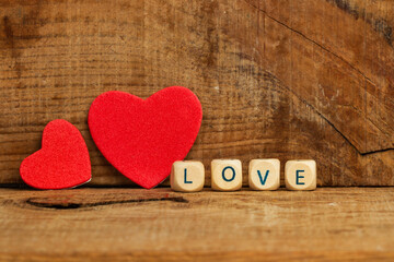 Dos corazones rojos sobre un fondo rústico de madera y con cubos de madera con la palabra love. Vista de frente. Copy space. Concepto: Día de San Valentín, matrimonio