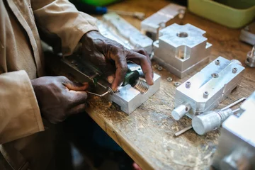 Gordijnen Hands of a man working with tools in a workshop in Uganda, Africa © Dennis