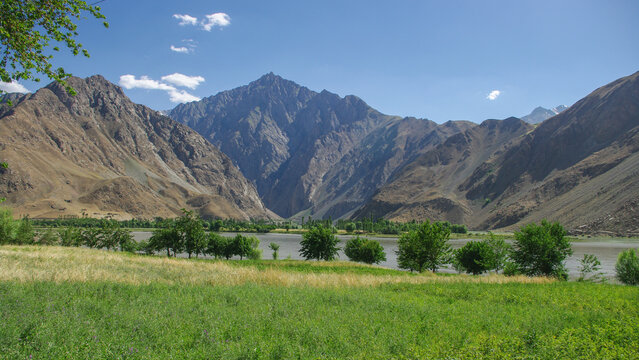 Mountain landscape view of Panj river valley with green fields, border between Tajikistan and Afghanistan, near Khorog, Gorno-Badakshan, Tajikistan Pamir