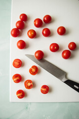 Naklejka na ściany i meble Cherry tomatoes lie on a light pink cutting board next to a knife on a blue background 