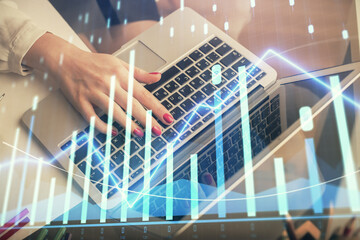Double exposure of woman hands typing on computer and financial graph hologram drawing. Stock market analysis concept.