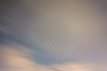 Night sky with clouds and stars, long exposure, motion blur in the clouds, stars shining through the thin layer of clouds.