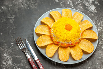 side view of salad on the right side with work and knife on side on dark grey table