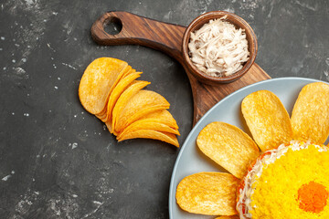 top close view of salad on right bottom side on plate stand with lemon and herbs on side on dark grey table