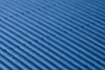 Background made of blue corrugated cardboard with diagonal stripes, shallow depth of field.