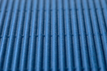 Background made of blue corrugated cardboard with vertical stripes, shallow depth of field.