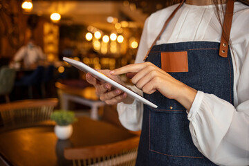 Waitress using digital tablet. Waitress working at a restaurant using a tablet computer . Putting her coffee shop on the social media map. Cafe owner using digital tablet