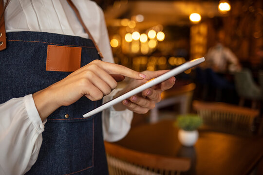 Waitress using digital tablet. Waitress working at a restaurant using a tablet computer . Putting her coffee shop on the social media map. Cafe owner using digital tablet