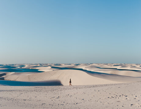 Solo female backpacker walks across the sand dunes of Lencois Maranhenses, miles and miles of sand dunes and lagoons in Maranhao, North-Eastern Brazil
