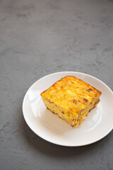 Homemade Cheesy Amish Breakfast Casserole on gray surface, low angle view. Copy space.