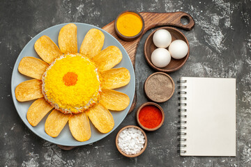 top view of salad on plate stand with herbs and notepad on side on dark grey table