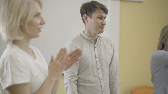 Smiling positive man playing acting game with groupmates. Portrait of handsome adult Caucasian actor training skills in auditorium. Role and talens concept.