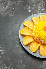side close view of salad with chips around on plate on dark grey background from right side