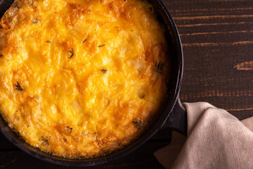 Frittata with cheese, mozzarella and stewed pumpkin in a cast iron pan on a wooden background