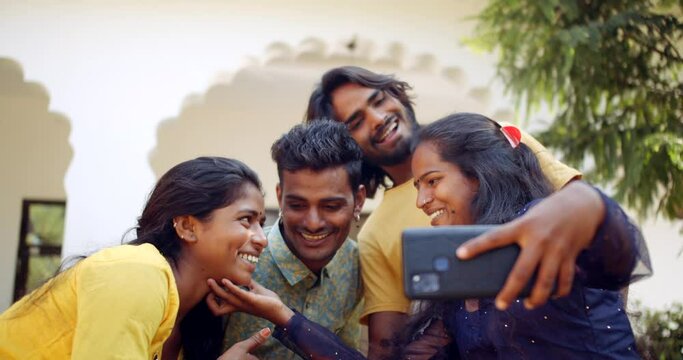 Slow-motion shot of Young adult females and males outside their university campus building taking a selfie photo video on their mobile phone camera smiling happy joyous 